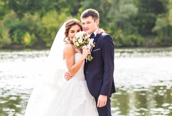 Весільна пара стоїть і обіймається біля озера . — стокове фото