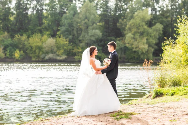 Matrimonio coppia in piedi e abbracci vicino lago . — Foto Stock