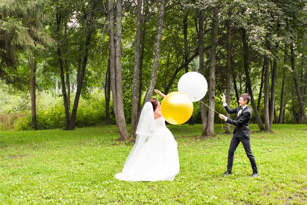Noivo e noiva com balões ao ar livre — Fotografia de Stock