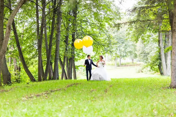 Brudgummen och bruden med ballonger utomhus — Stockfoto