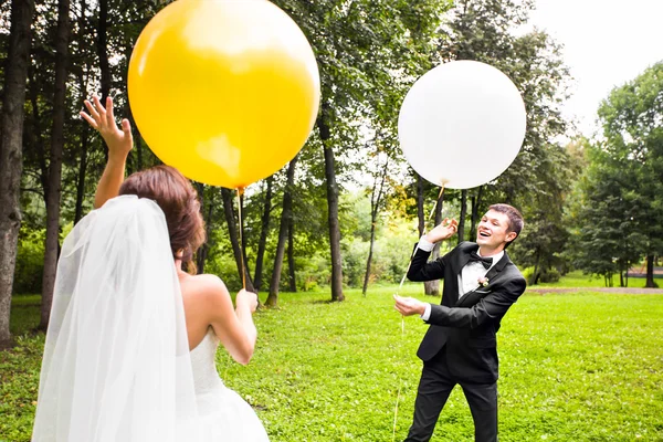 Noivo e noiva com balões ao ar livre — Fotografia de Stock