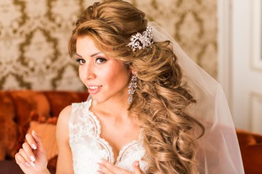 Güzel genç gelin kanepede oturan bir düğün buketi ile.