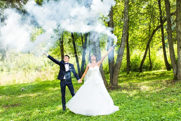 Casamento, amor, relacionamentos, casamento. Noiva sorridente e noivo com fumaça azul — Fotografia de Stock