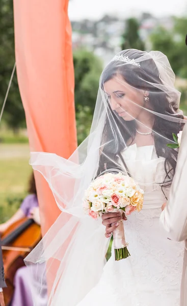 Noiva de beleza em vestido de noiva com buquê e véu de renda sobre a natureza. — Fotografia de Stock