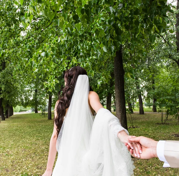 Bela noiva jovem segura a mão de um homem ao ar livre. Segue-me. — Fotografia de Stock