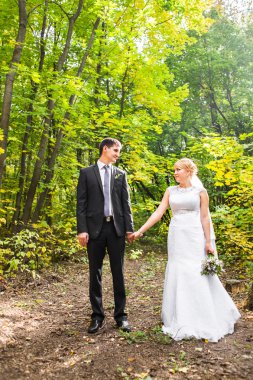 Gelin ve damat dışarıda el ele tutuşuyorlar.