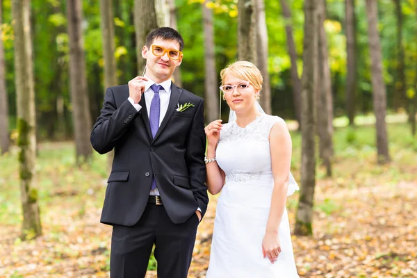 Aprilscherz. Hochzeitspaar posiert mit Stocklippen, Maske. — Stockfoto