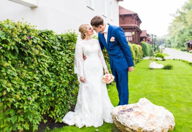 Şık gelin ve damat düğün günü dışarıda birlikte poz veriyorlar.