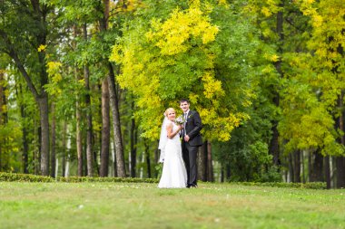 iki sonra düğün kıyafetleri ile bir buket çiçek, gelin ve damat açık havada