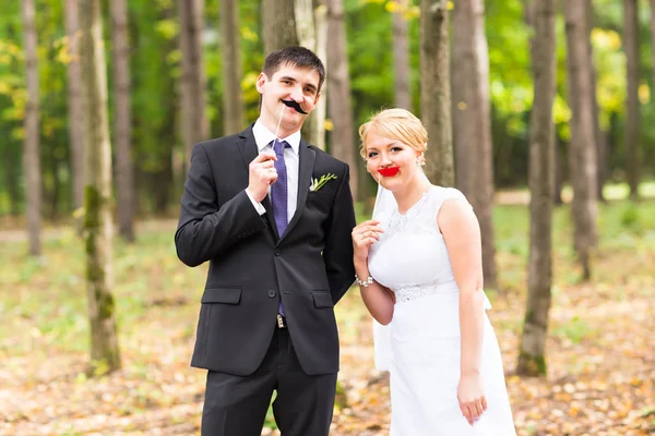 April Fools Day. Bruidspaar poseren met stok lippen, maskeren. — Stockfoto