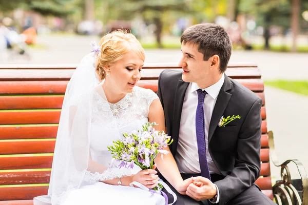 Casal em traje de casamento com um buquê de flores, noiva e noivo ao ar livre — Fotografia de Stock