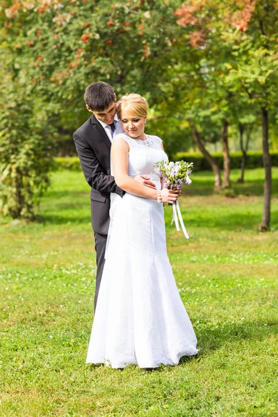 Couple en tenue de mariage avec un bouquet de fleurs, mariée et marié à l'extérieur — Photo
