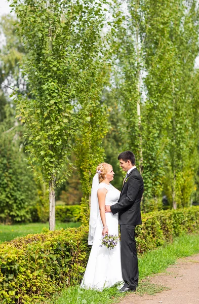 Couple en tenue de mariage avec un bouquet de fleurs, mariée et marié à l'extérieur — Photo