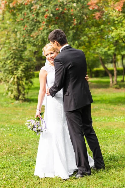 Beautiful wedding couple outdoors. They kiss and hug each other Royalty Free Stock Images