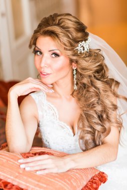 Güzel genç gelin kanepede oturan bir düğün buketi ile.