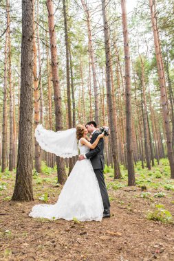 Şık gelin ve damat düğün günü dışarıda birlikte poz veriyorlar.