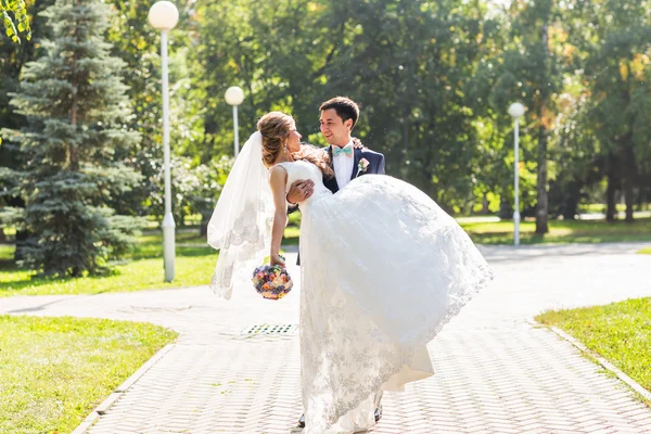 Casamento casal abraçando, a noiva segurando um buquê de flores, noivo abraçando-a — Fotografia de Stock