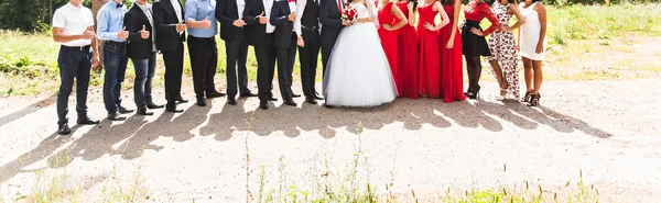 Bruid en bruidegom staan met gasten in de tuin — Stockfoto