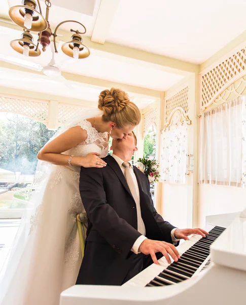 Pareja de boda tocando un piano en la habitación — Foto de Stock
