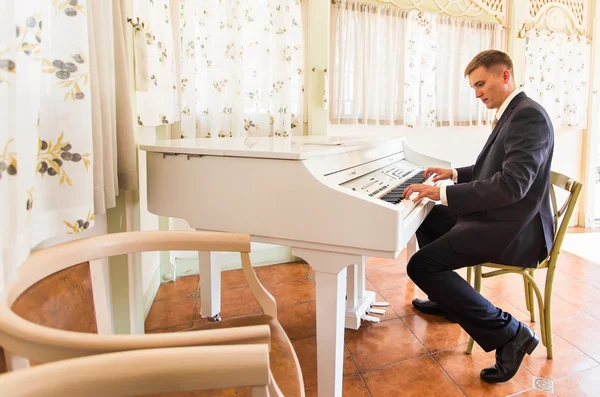 Brudgummen spelar på ett piano i rummet — Stockfoto