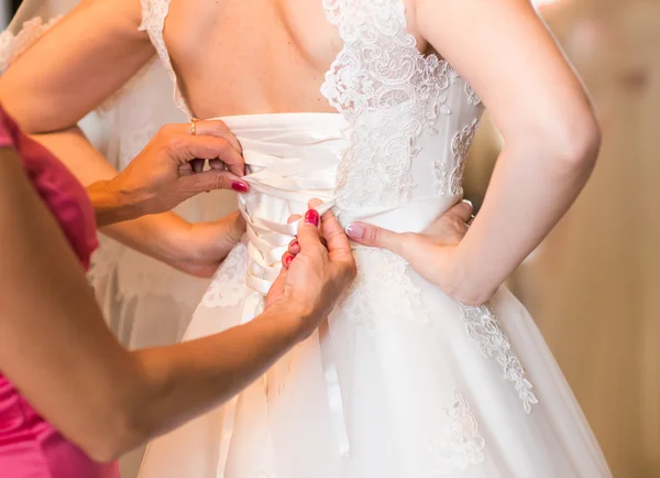 Družičky pomáhají nevěstě šněrováním šaty — Stock fotografie