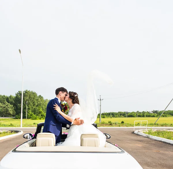 De bruidegom en de bruid in een witte Cabrio auto — Stockfoto