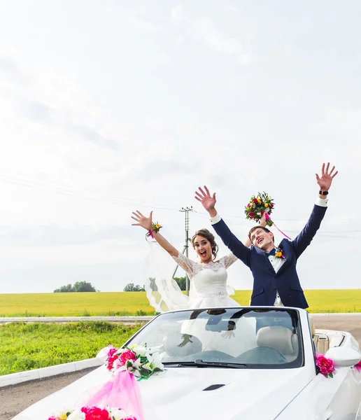 Ο γαμπρός και η νύφη σε ένα λευκό μετατρέψιμο αυτοκίνητο — Φωτογραφία Αρχείου