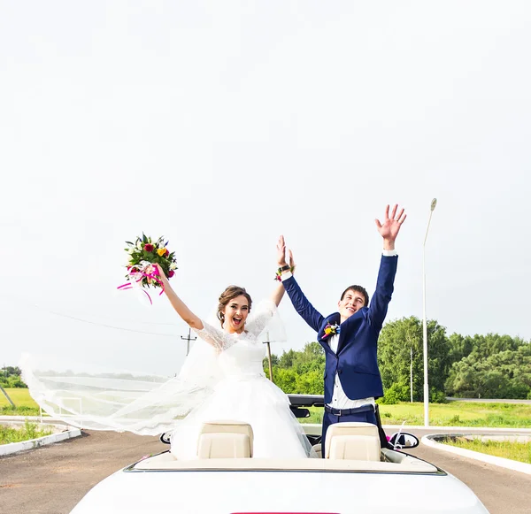 Brudgummen och bruden i en vit cabriolet bil — Stockfoto