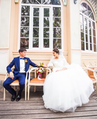 Şık gelin ve damat düğün günü dışarıda birlikte poz veriyorlar.