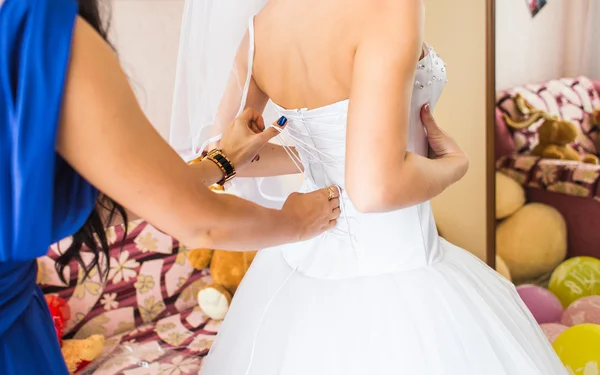 Bridesmaid is helping the bride to dress — Stock Photo, Image
