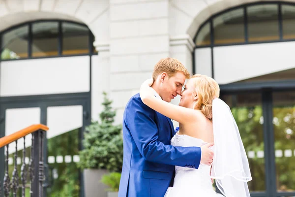 Knappe bruidegom kussen van de mooie bruid buitenshuis — Stockfoto