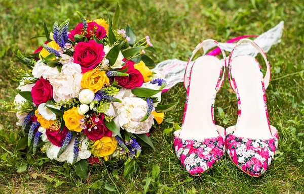 Весільний букет і взуття на траві — стокове фото