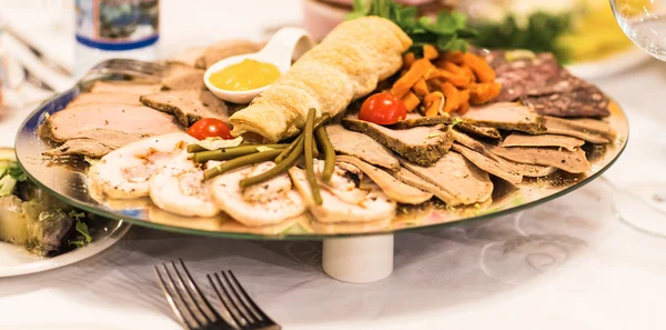 Блюдо из нарезанной ветчины, салями и вяленого мяса с растительным декором на праздничном столе . — стоковое фото