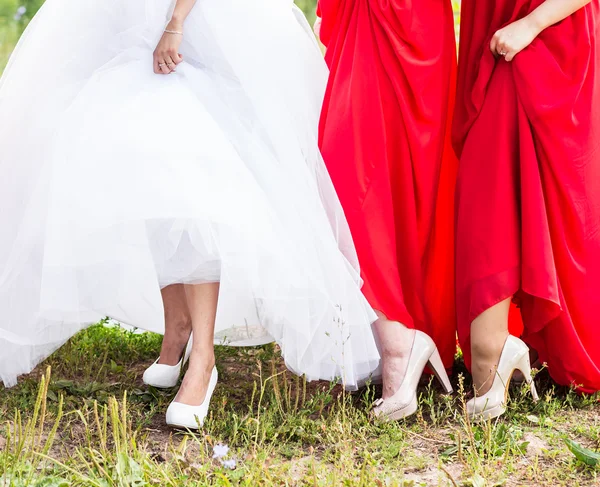 Sposa e damigelle d'onore mostrare le loro scarpe al matrimonio . — Foto Stock