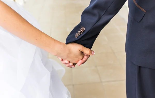 Close-up van bruid en bruidegom buitenshuis hand in hand. — Stockfoto