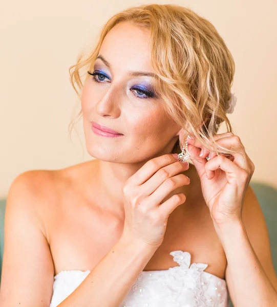 Mooie elegante bruid zetten oorbellen close-up, voorbereiding bruiloft. — Stockfoto