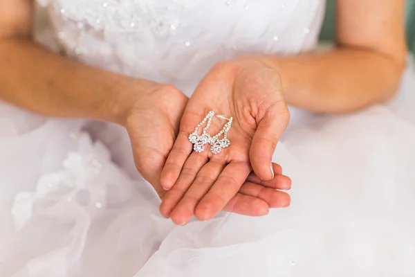 Pendientes en una mano femenina —  Fotos de Stock