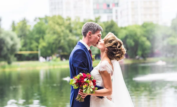 Красива брюнетка наречений цілує красиву наречену у весільній сукні — стокове фото