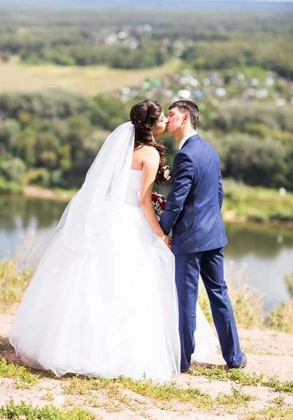 Bruidegom kussen bruid buitenshuis — Stockfoto