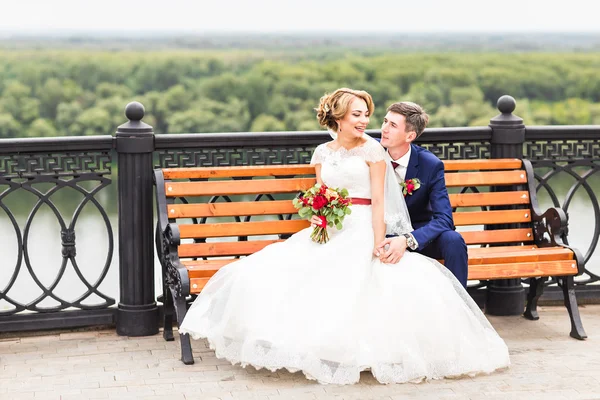 Bruidspaar knuffelen, het houden van een boeket bloemen, bruid bruidegom omarmen haar buitenshuis — Stockfoto