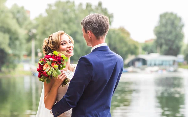 Bruid en bruidegom op de bruiloft dag buiten lopen. Gelukkig jonggehuwden omarmen. Verliefde paar. — Stockfoto