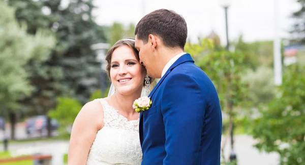 Hermosa novia y novio abrazando en su boda al aire libre — Foto de Stock