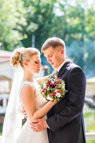 Bela noiva e noivo abraçando em seu dia de casamento ao ar livre — Fotografia de Stock