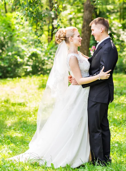 Mariée et marié le jour du mariage marchant à l'extérieur. Heureux jeunes mariés embrassant. Couple aimant . — Photo