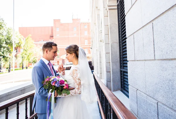 Casamento casal abraçando, a noiva segurando um buquê de flores, noivo abraçando-a ao ar livre — Fotografia de Stock