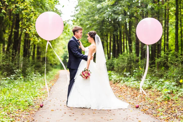 Noiva e noivo no dia do casamento andando ao ar livre. Feliz abraço dos recém-casados. Casal amoroso . — Fotografia de Stock