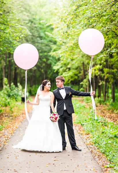 Casamento casal abraçando, a noiva segurando um buquê de flores, noivo abraçando-a ao ar livre — Fotografia de Stock