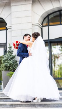 Onu açık havada kucaklayan Düğün çifti, sarılma bir buket çiçek, holding gelin damat