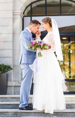 Onu açık havada kucaklayan Düğün çifti, sarılma bir buket çiçek, holding gelin damat