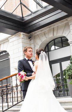 Onu açık havada kucaklayan Düğün çifti, sarılma bir buket çiçek, holding gelin damat